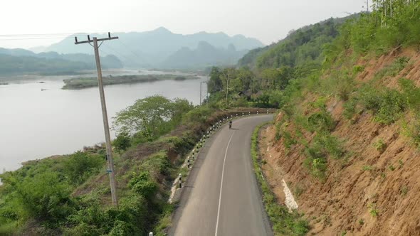 Aerial view of Motorcyclist on road next to Mekong River, Laos  alt