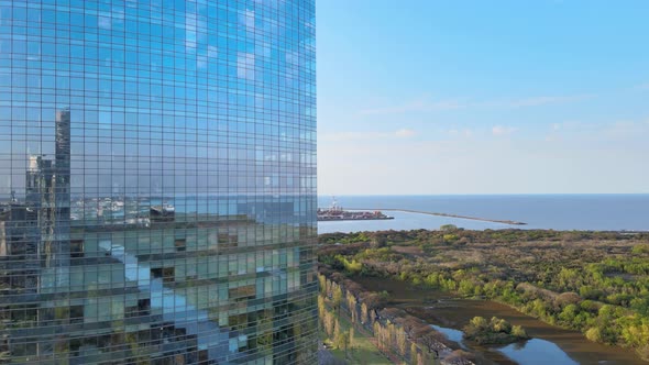 Sinking aerial of skyscraper, water and green landscape, Buenos Aires alt
