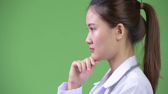 Profile View of Young Happy Beautiful Asian Woman Doctor Thinking alt