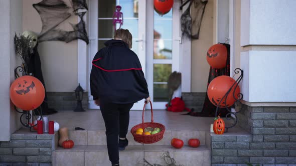 Back View Boy with Basket Walking to Decorated House on Halloween Entering alt