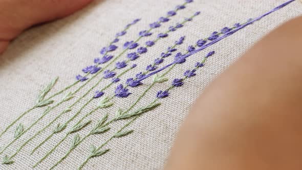 Woman makes embroidery a beautiful picture of lavender flowers. Handmade craft embroidery. alt