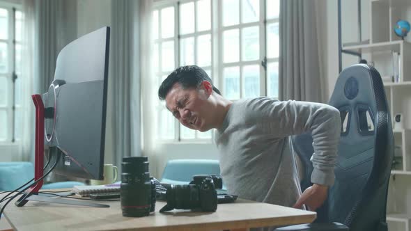 Asian Cameraman Having Backache While Using Desktop Computer For Working At Home alt