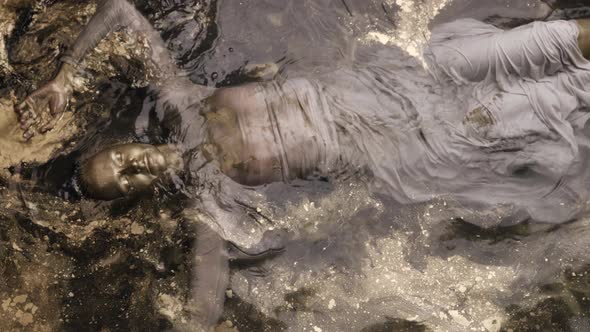 A Woman Submerged in Water Covered All Over with Gold Paint alt