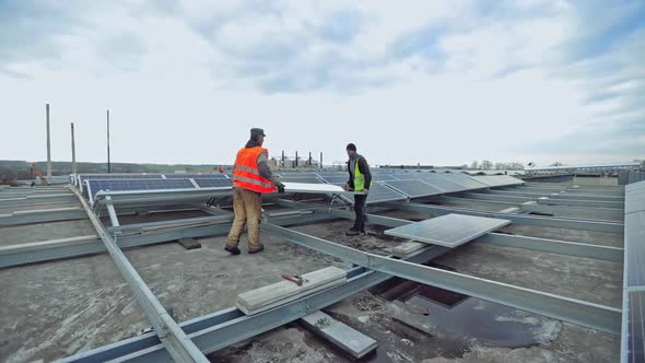 Technicians installing solar panel on metal base alt