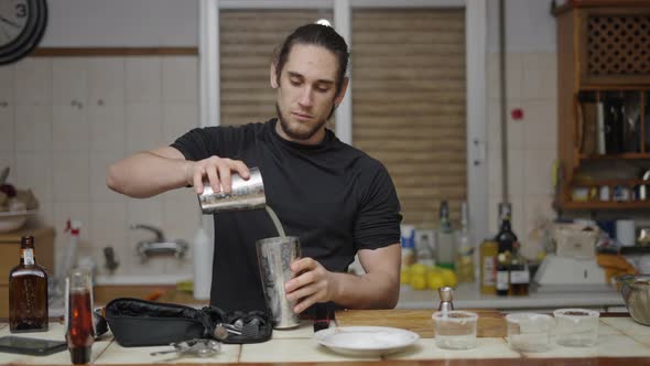 Handsome Barman Mixing Lime Juice with Alcohol in a Cocktail Shaker and Closing It to Shake It alt