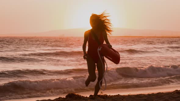 Female lifeguard running along the beach alt