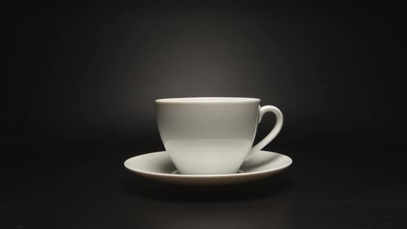 White coffee cup is rotating on black background