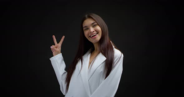 Businesswoman Shows Two Fingers or a Victorious Gesture on a Black Background
