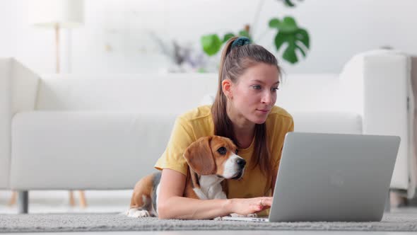 Woman Working with Laptop and Lying on Floor with Dog at Apartment Room Spbi alt