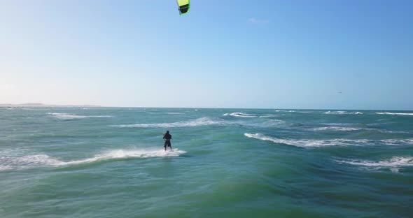 Aerial drone view of a man kiteboarding on a kite board alt