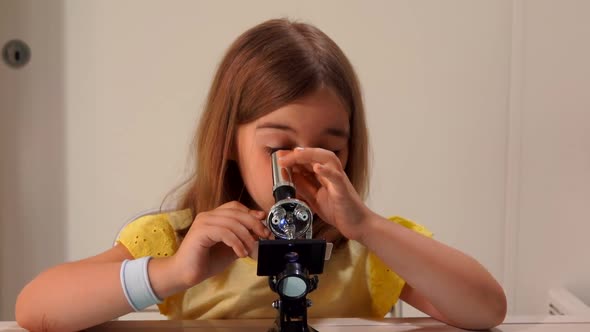 Cute Girl is Looking Look Through the Microscope in a White Sunlit Room alt