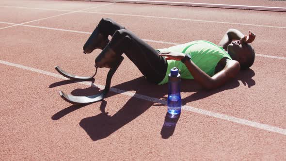 Disabled mixed race man with prosthetic legs lying on race track alt