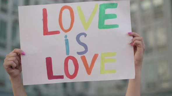 Close-up of Raised Love Is Love Banner in Female Caucasian Hands. Unrecognizable Lesbian Activist alt