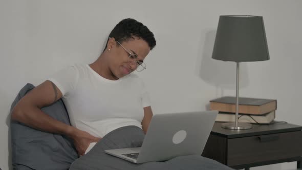 African Woman Having Back Pain While Using Laptop in Bed alt