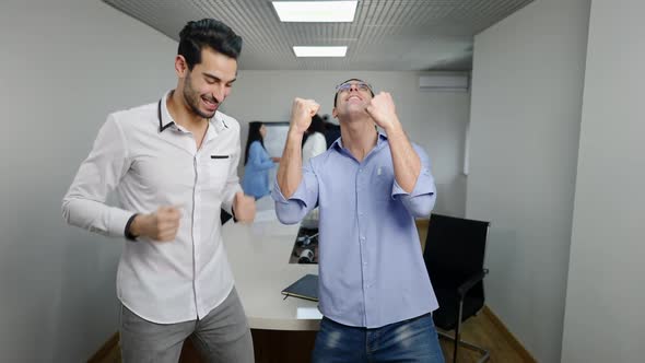 Positive Successful Middle Eastern Men Rejoicing Startup Success in Office with Blurred Women alt