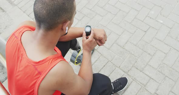 Side view man with prosthetic leg looking at his watch alt