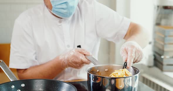 Chef Works with Face Medical Mask in Restaurant Cooking Pasta