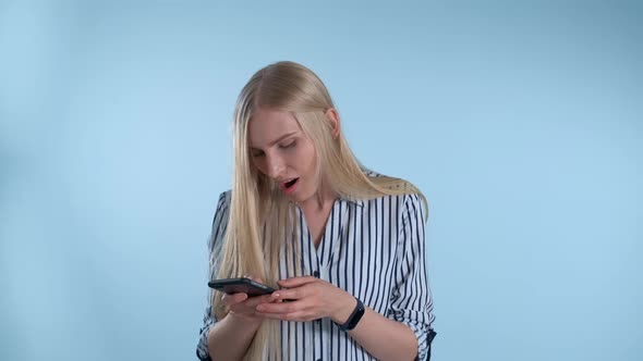 Attractive Young Woman Is Very Delighted with Something Looking on Smartphone alt