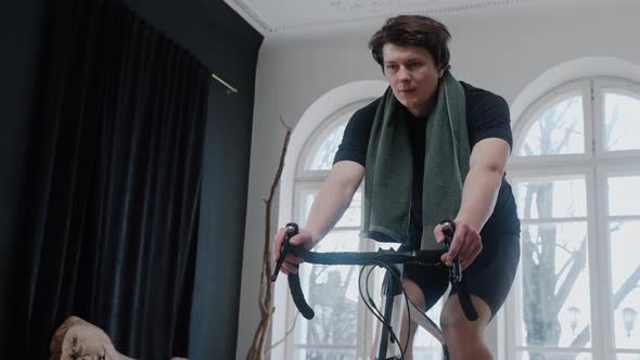 A Cyclist Training on an Exercise Bike at Home and Breathing Heavily