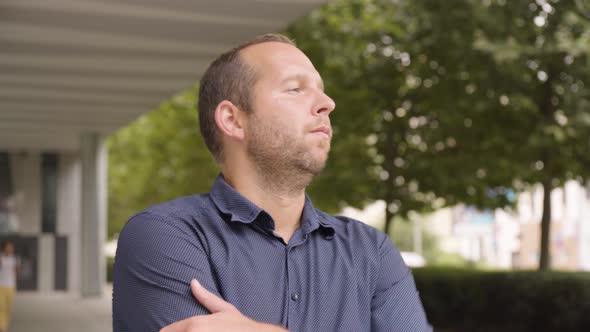 A Caucasian Man Looks Around By an Office Building in an Urban Area  Closeup