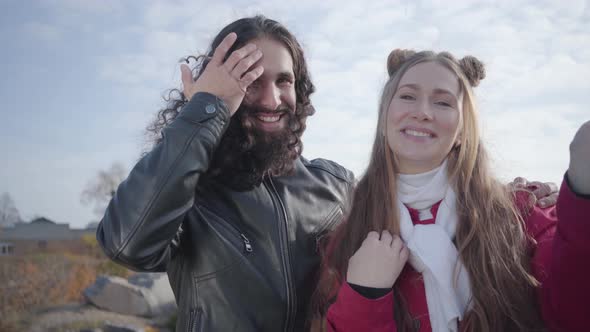 Portrait of Smiling Hippie Couple Waving at Camera and Talking. Close-up Faces of Young Middle alt