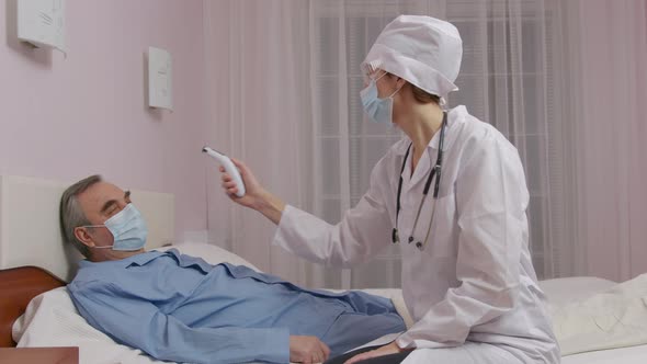 Close Up of Caucasian Female Doctor Hand Measuring Temperature of Middleaged Male Patient alt