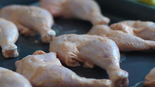 Cooking chicken legs on a baking sheet at home. Raw chicken legs in a frying pan.Selective focus. Fr alt