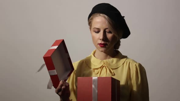 Stylish woman with red gift box on grey background