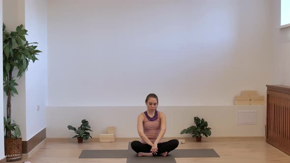 The Girl in the Yoga Room Does a Warm-up of Hands on a Yoga Mat. alt