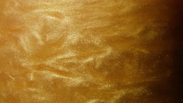 Macro shot of gold glitter. Slow mo. Amazing background. 4K. Gold liquid. Boke.