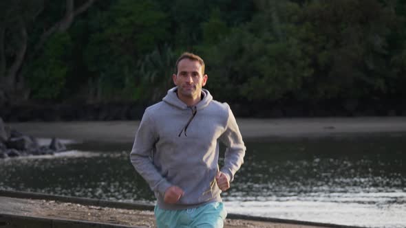 Slow motion shot of fit caucasian man jogging on the beach in Auckland, New Zealand alt
