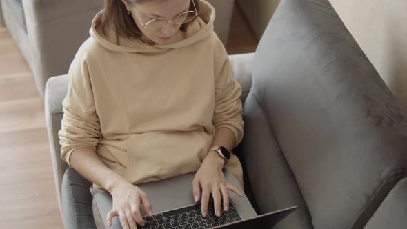 Girl with Glasses Uses Laptop at Home