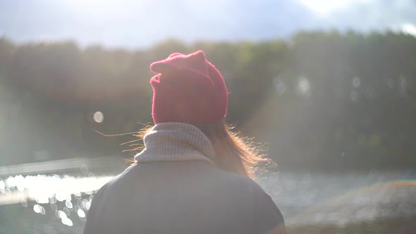 Woman Stands with Her Back in the Frame on the River Bank alt