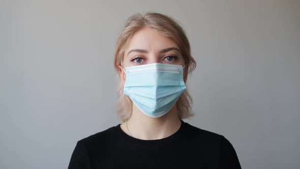Portrait of a beautiful woman with blue eyes wearing a medical mask at home