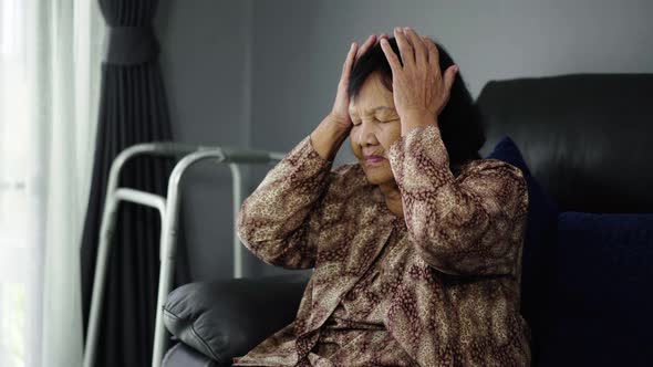 senior woman having a headache in living room