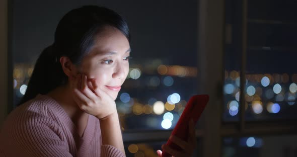 Woman look at mobile phone at night inside living room