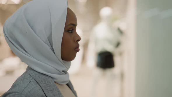 AfricanAmerican Woman with White Hijab Walks Past Stores alt