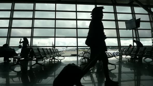 Travelers Walking Along Window in Airport Terminal, People Silhouettes Walking. alt