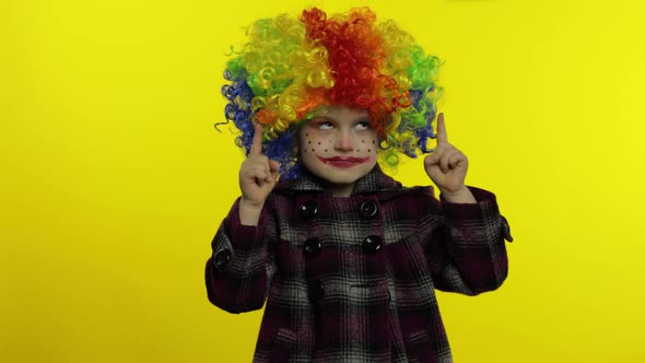 Little Child Girl Clown in Colorful Wig Making Silly Face with Eyes. Fool Around, Smiling. Halloween alt