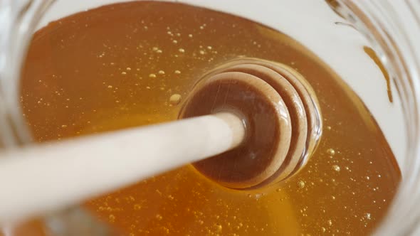 Spiral spoon  dipped in glass honey jar close-up 4K 2160p 30fps UltraHD footage - Wooden  dipper in  alt