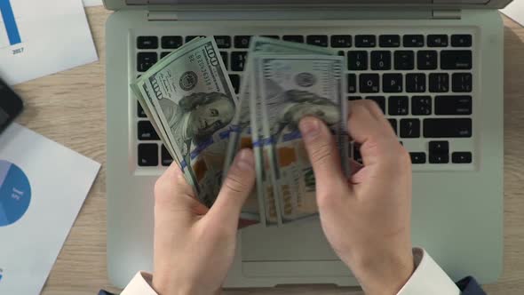 Close-Up of Businessperson Counting Dollar Banknotes at Workplace, Slow-Motion alt