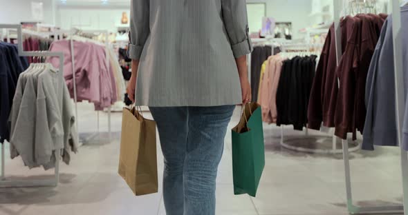 Young Woman in Blue Jeans Walking with Shopping Bags alt