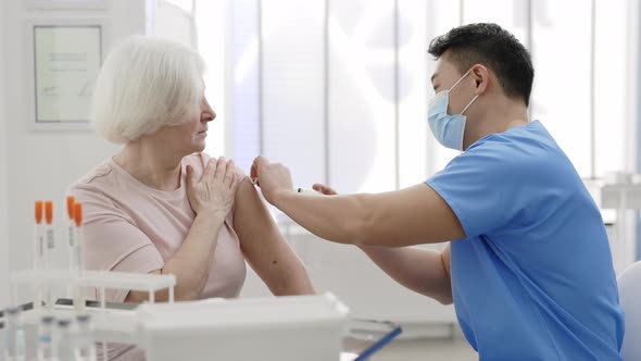 Close Up View of Male Medical Worker in Protective Mask Disinfecting Patient Shoulder While alt