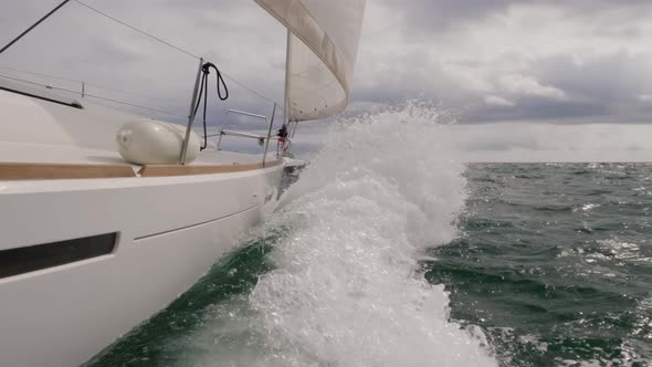 Sailboat Sailing with Huge Waves Breaking to the Camera