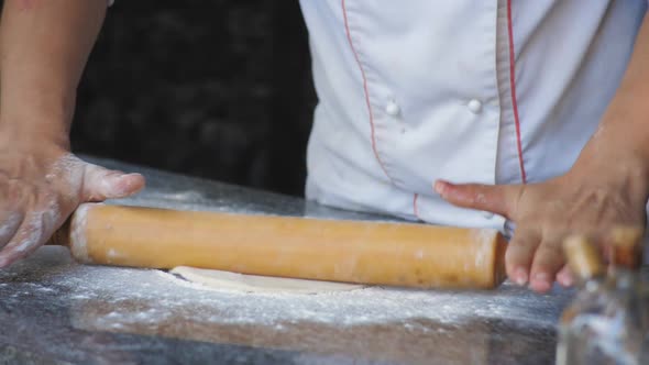 A Male Chef in a Restaurant Rolls Out the Dough with a Rolling Pin for Making Focaccia