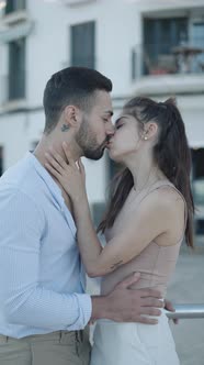 Smiling Hispanic Couple Talking and Kissing on Street alt