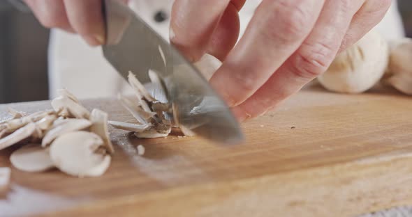 Close up of a chef knife slicing champignon mushrooms alt