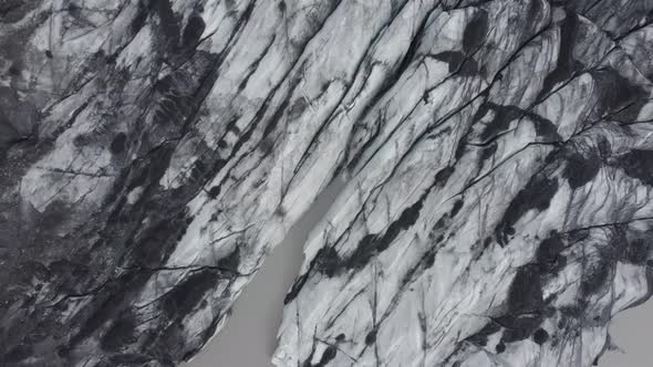 Aerial view over darkened, sooty glacier surface, in Iceland - overhead, drone shot alt