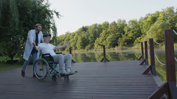 Medic and Elderly Man Look at Fascinating Surrounding of the Park alt
