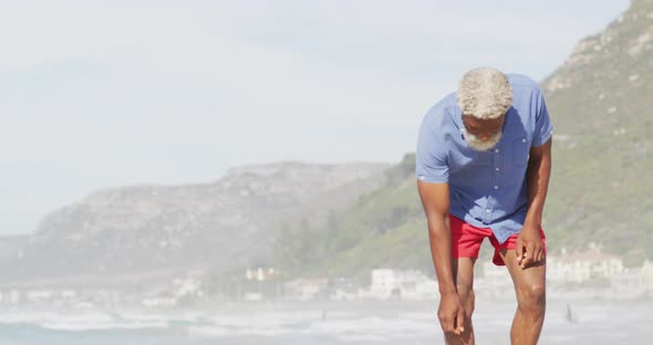 Senior african american man walking alone on sunny beach alt